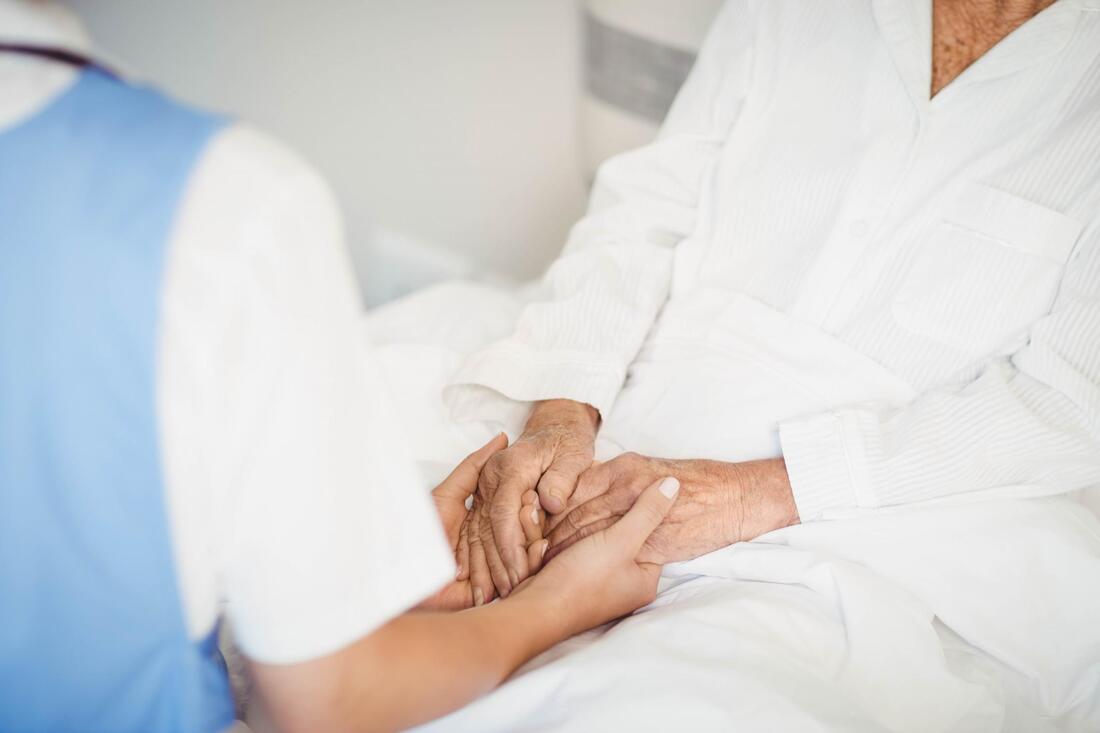 a woman holding the hand of a man in a hospital bed